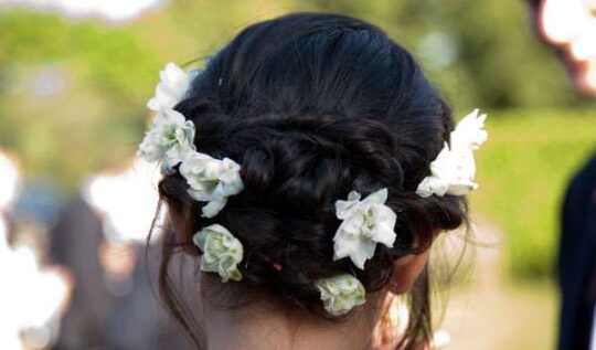A close-up of an intricate bridal updo adorned with fresh white flowers, showcasing the elegant and personalised hair styling services by Jyn San Hair & Makeup in Somerset for weddings and special occasions.
